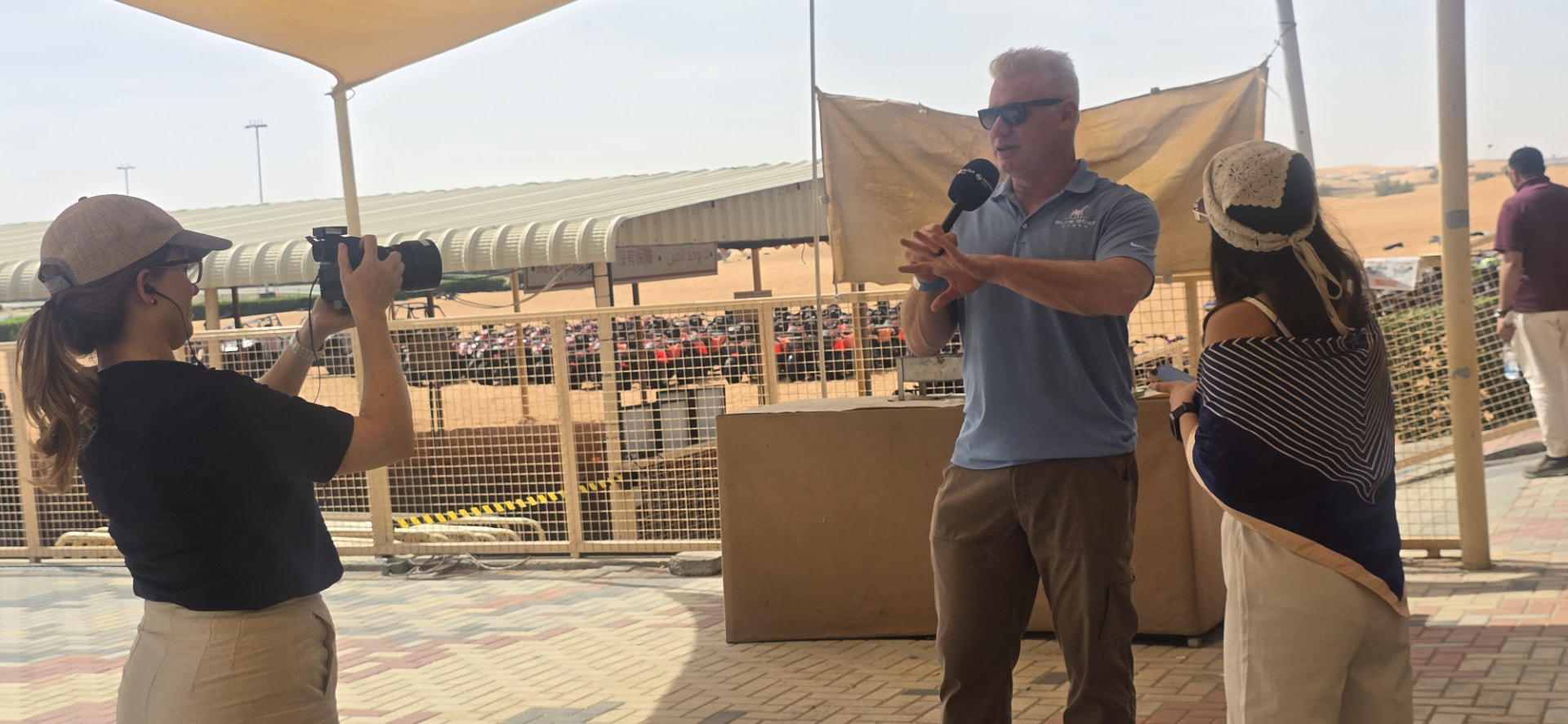 Christian Espinosa speaking into a microphone while being filmed outdoors during the MedTech World Dubai desert tour