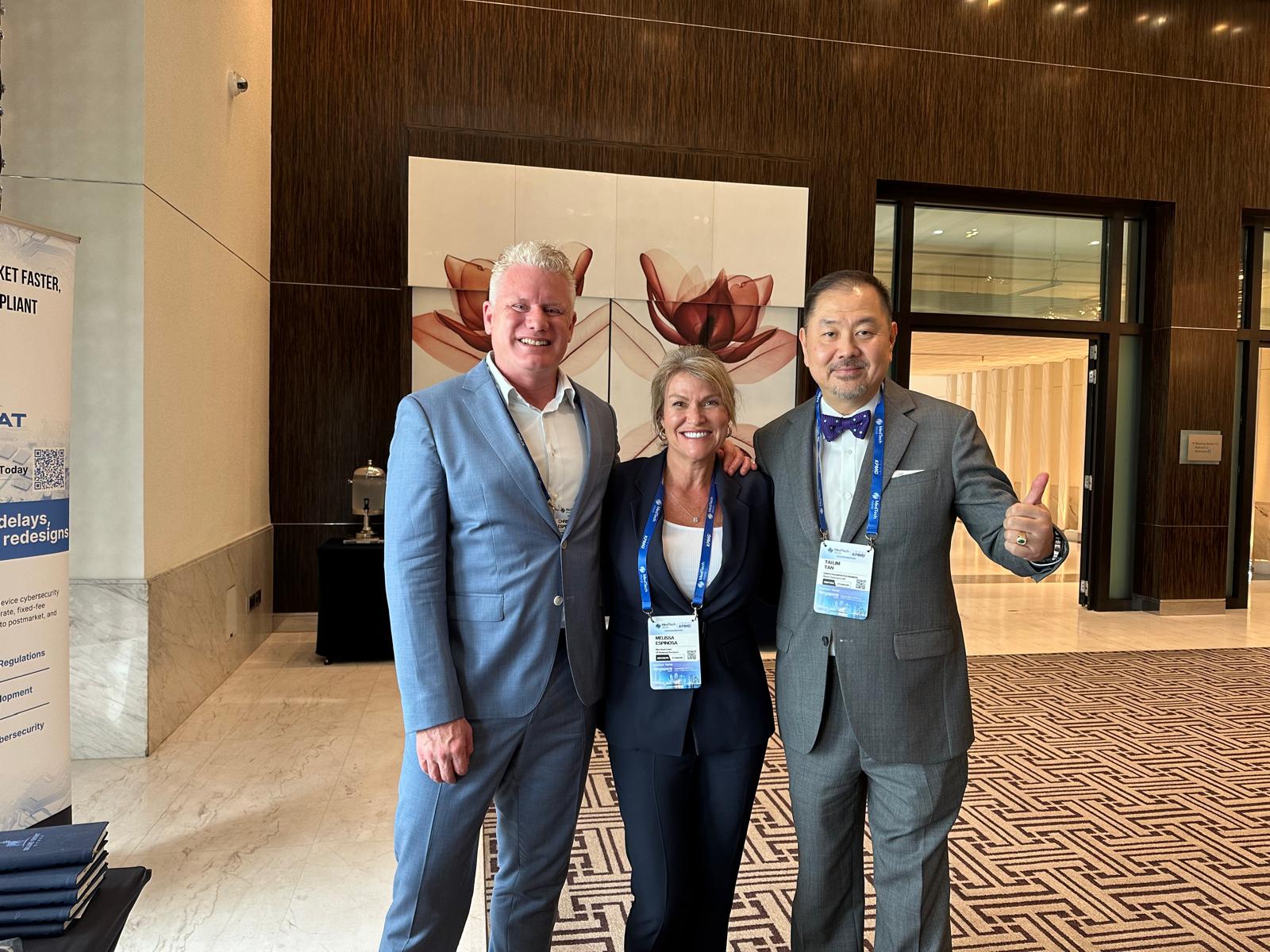Christian and Melissa Espinosa with Tai Tan giving a thumbs up in a conference hotel lobby