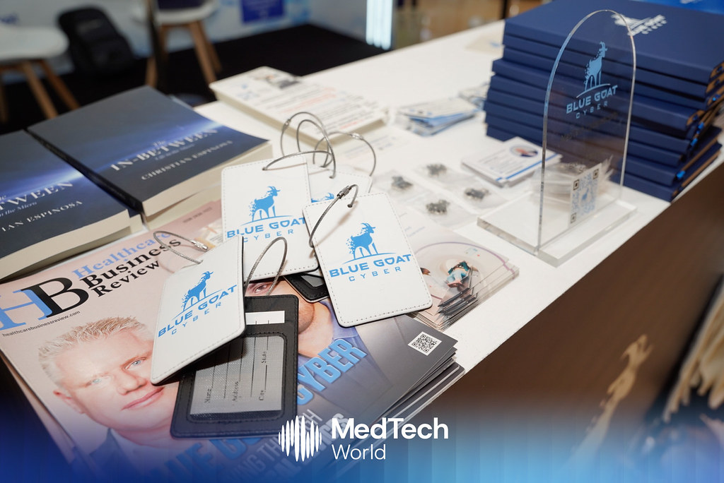 Blue Goat Cyber luggage tags, books by Christian Espinosa, and magazines on the booth table at MedTech World