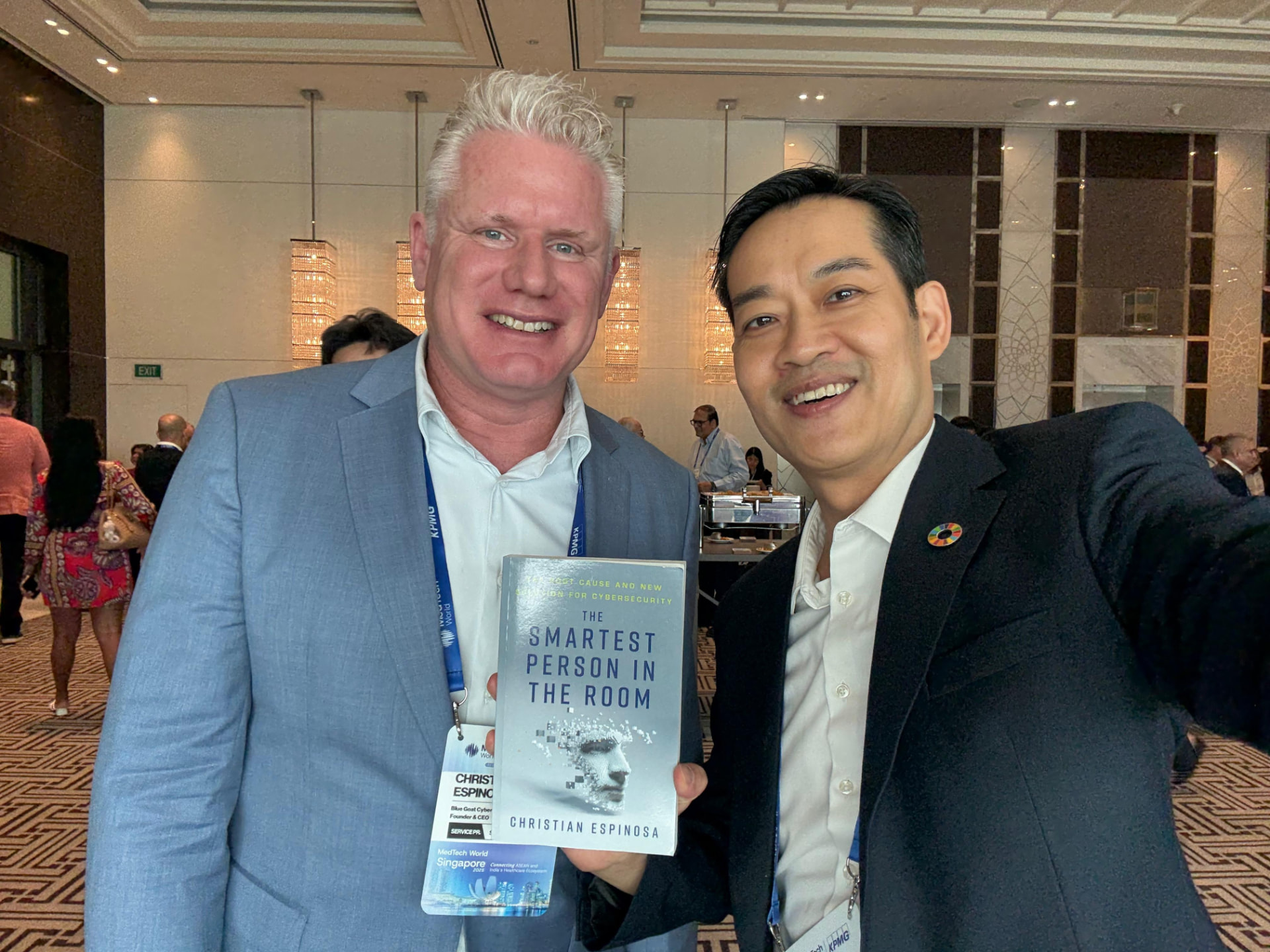 Christian Espinosa and William holding a signed copy of The Smartest Person in the Room at a conference