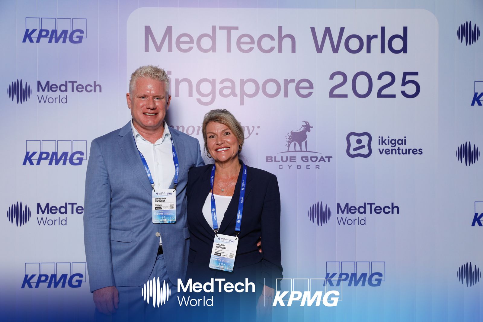 Christian and Melissa Espinosa in evening wear at the MedTech World Singapore gala, standing in front of the sponsor backdrop that includes the Blue Goat Cyber logo