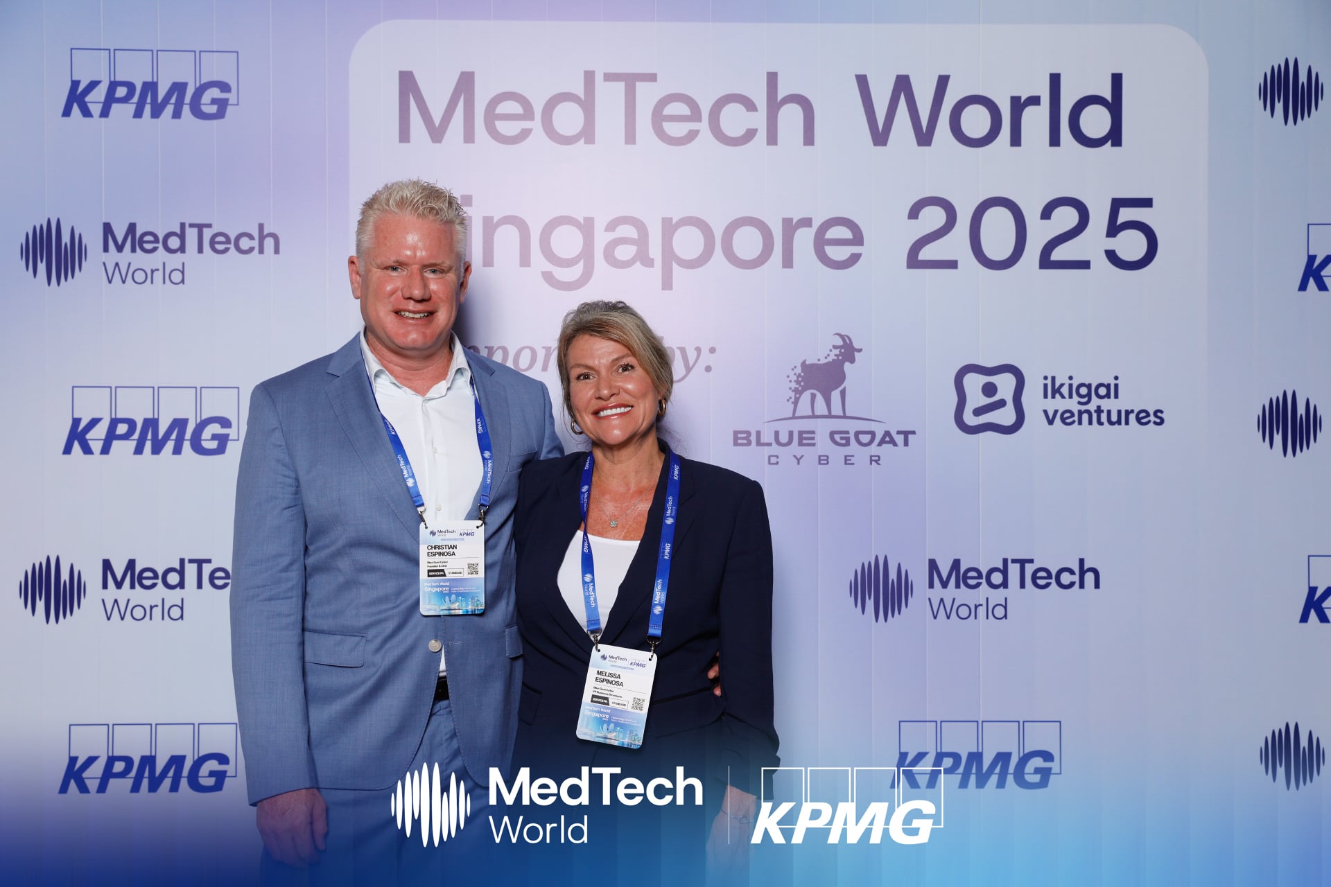 Christian and Melissa Espinosa in evening wear at the MedTech World Singapore gala, standing in front of the sponsor backdrop that includes the Blue Goat Cyber logo